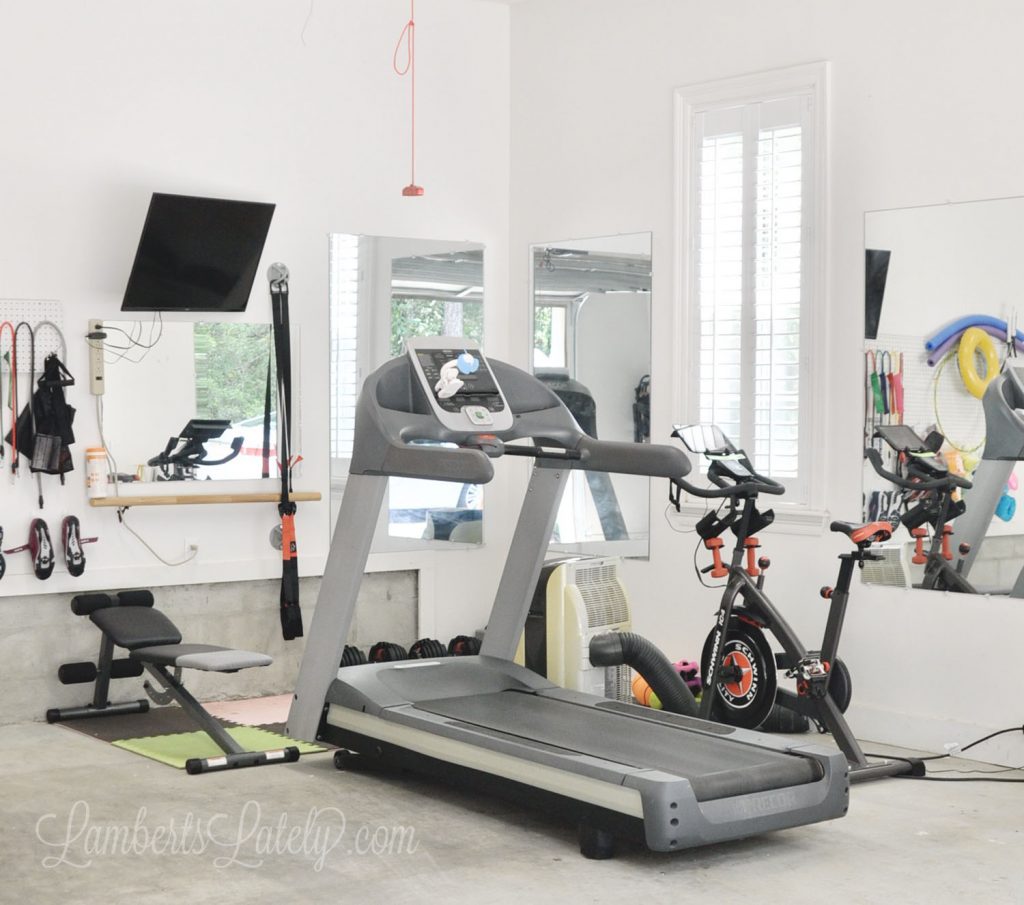 This garage home gym shows how to turn a small space into a functional exercise area. Has a bike, treadmill, strength/weight training area, and TV for Peloton/online workouts.