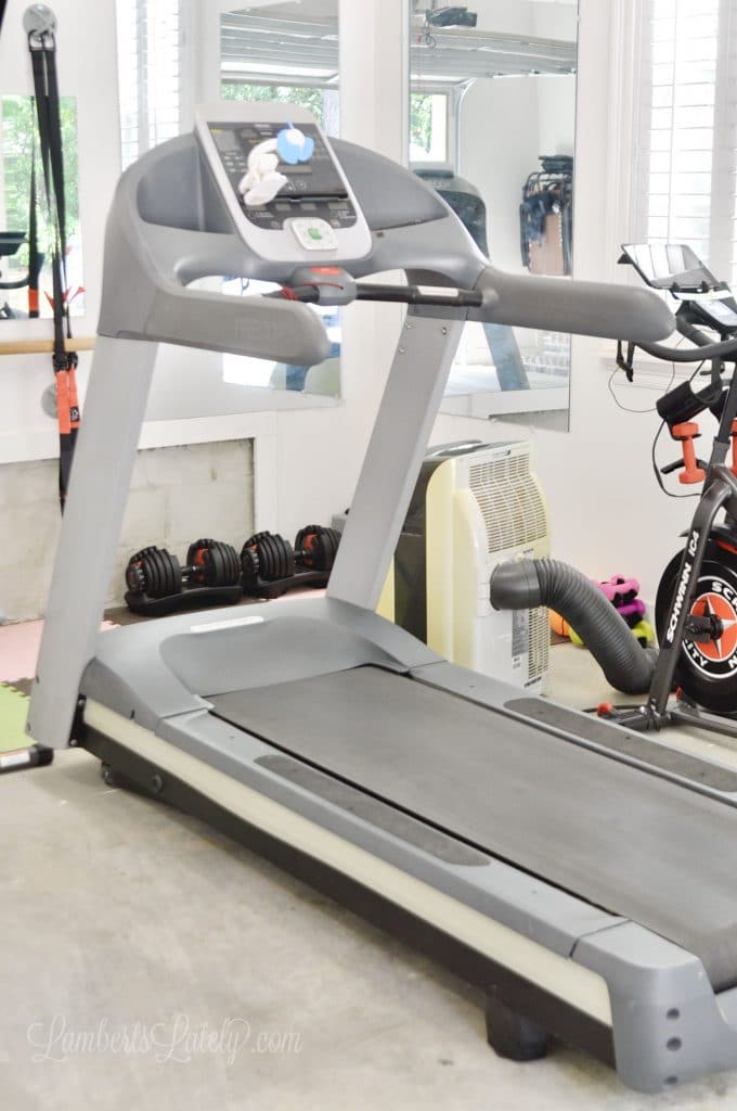  This garage home gym shows how to turn a small space into a functional exercise area. Has a bike, treadmill, strength/weight training area, and TV for Peloton/online workouts.
